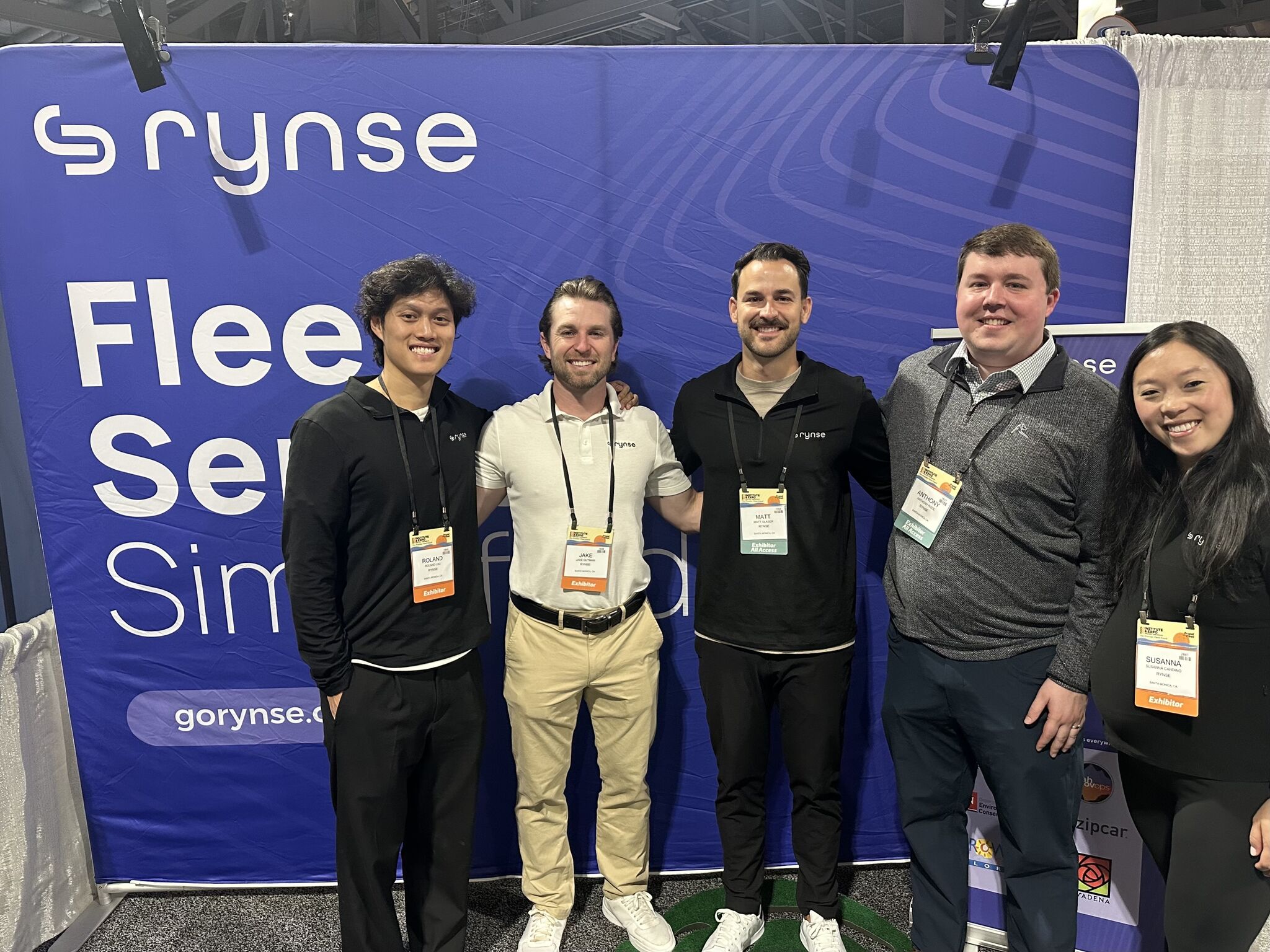 The Rynse team poses in front of the booth’s backdrop. 