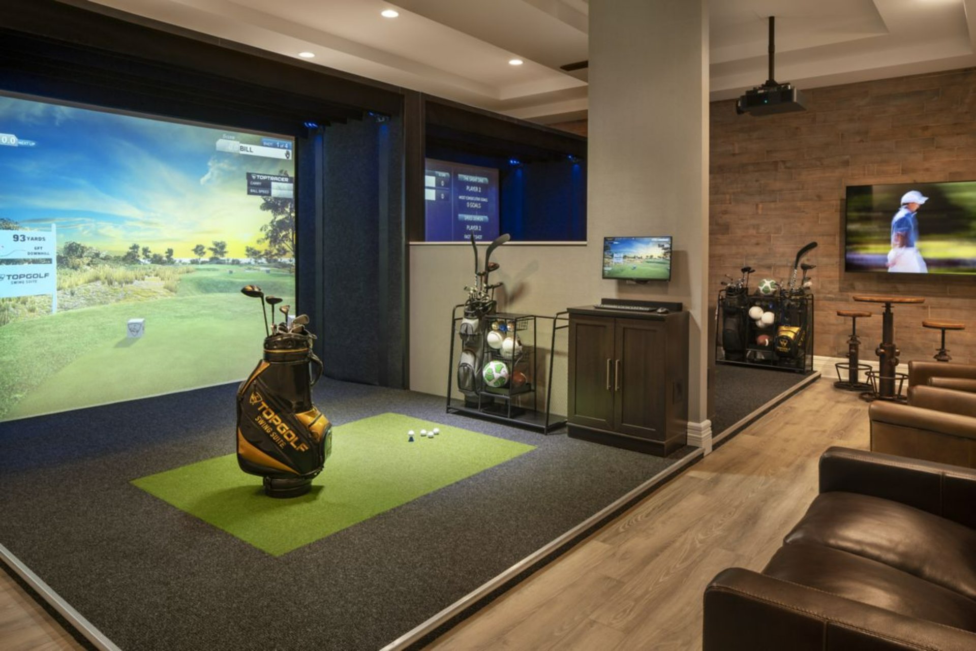 Topgolf simulator screen displaying a virtual driving range, with golf clubs positioned in front of the screen.